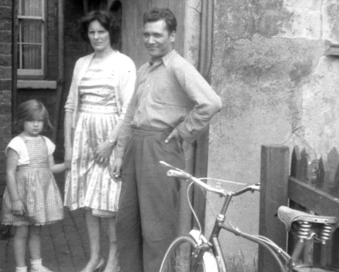 Family with bicycle outside a terraced house, newly arrived in England