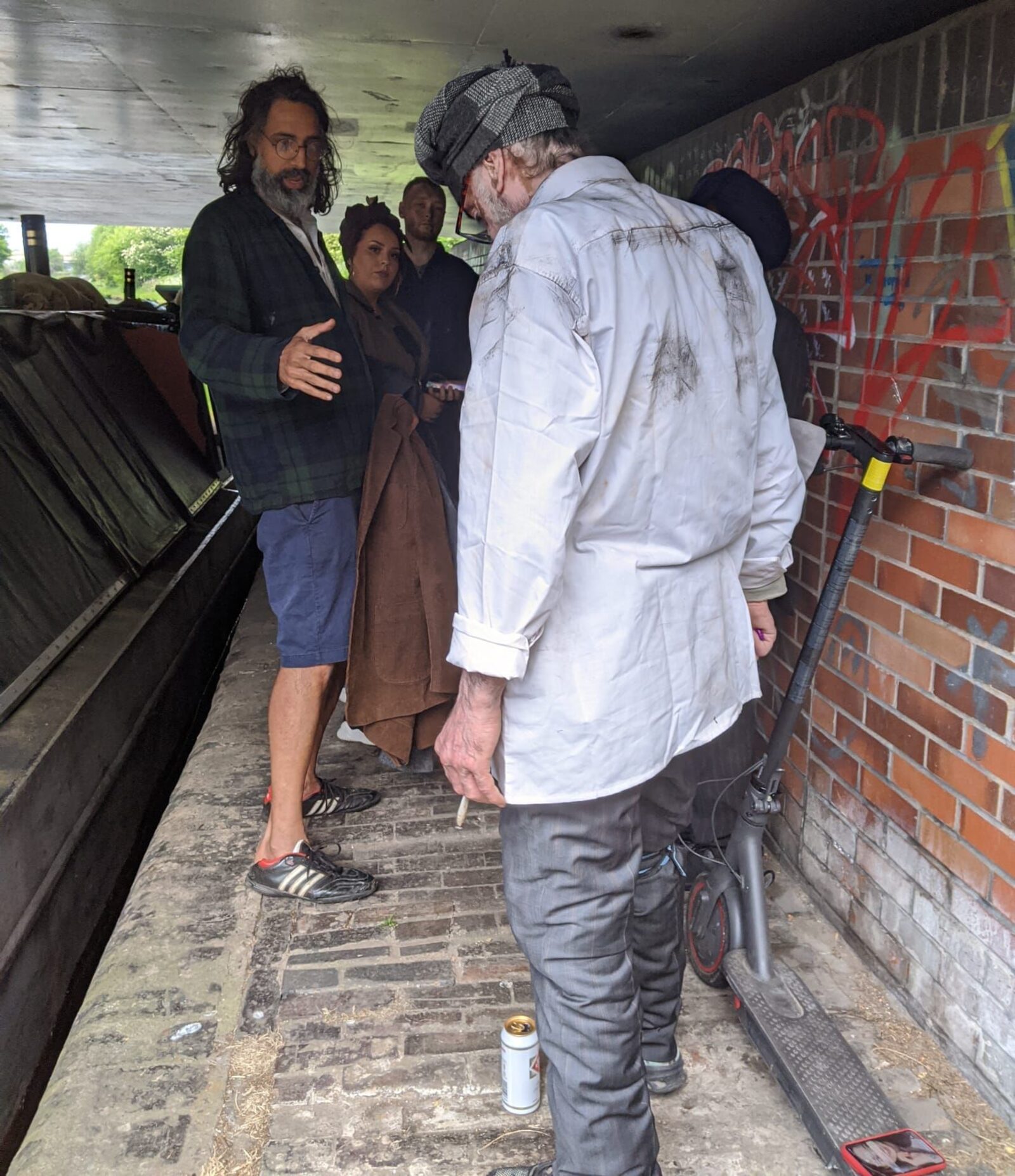 Director briefing cast members under a canal bridge between setups