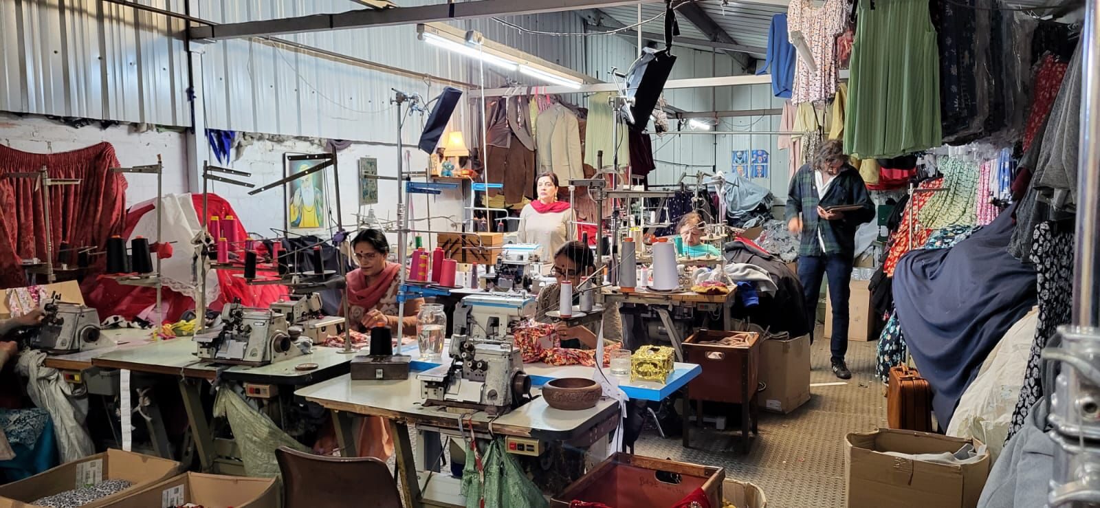 The sewing workshop set, Guru Nanak portrait, sewing machines, and hanging garments