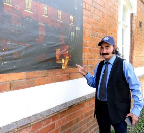 Billy Dosanjh in front of an Exiles print at a community exhibition