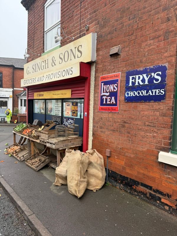 G. Singh & Sons shopfront with period signage and produce — the set fully dressed