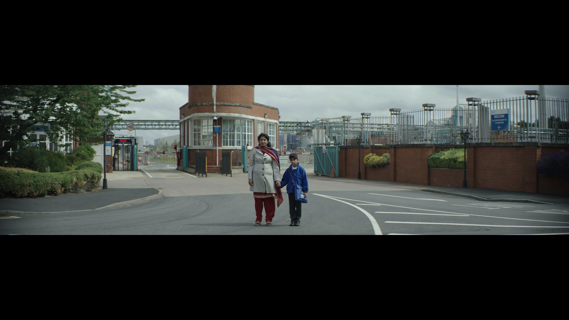 Sheeru and Indi outside the factory gates — still from Indi (2022)