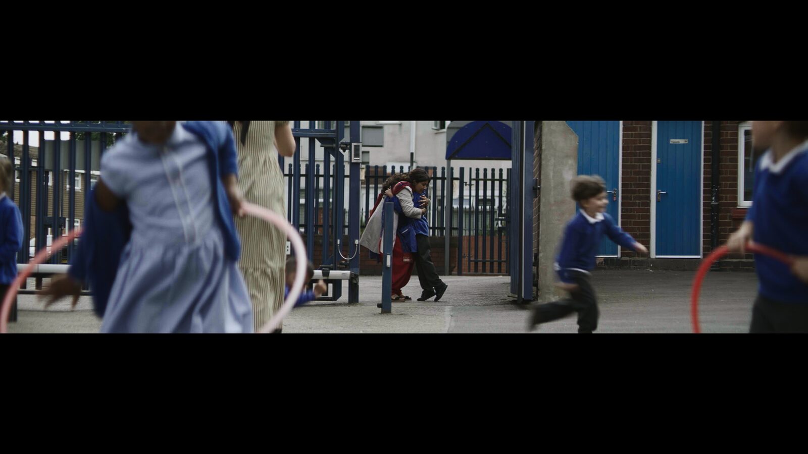 Sheeru arrives at the school gate as children play in the yard