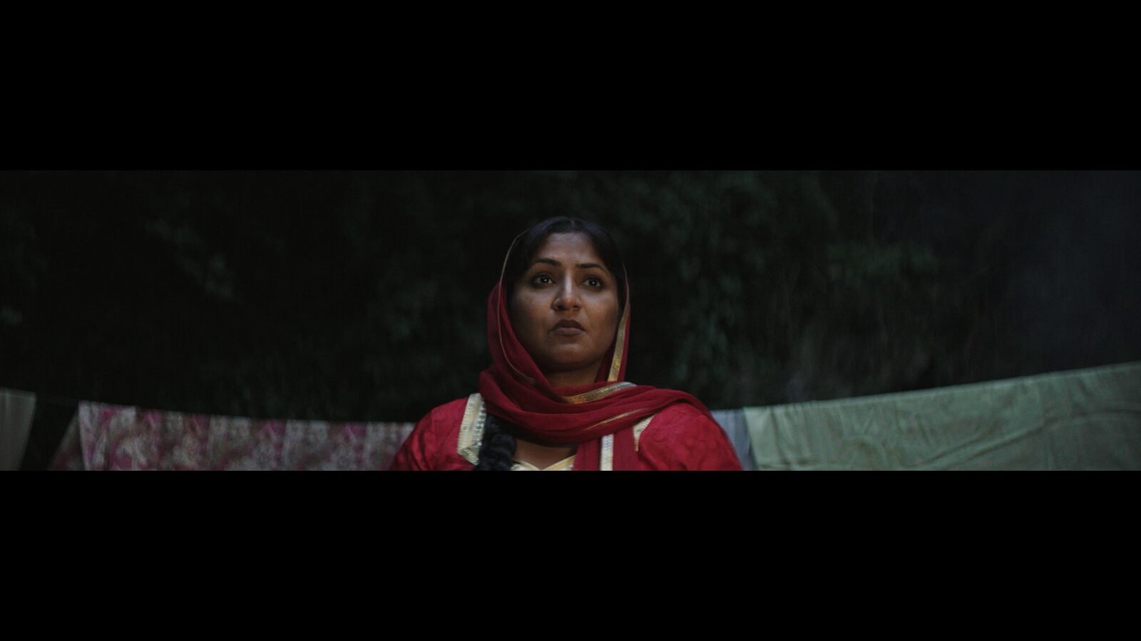 Sheeru in the in-between world — a portrait in red dupatta against the night