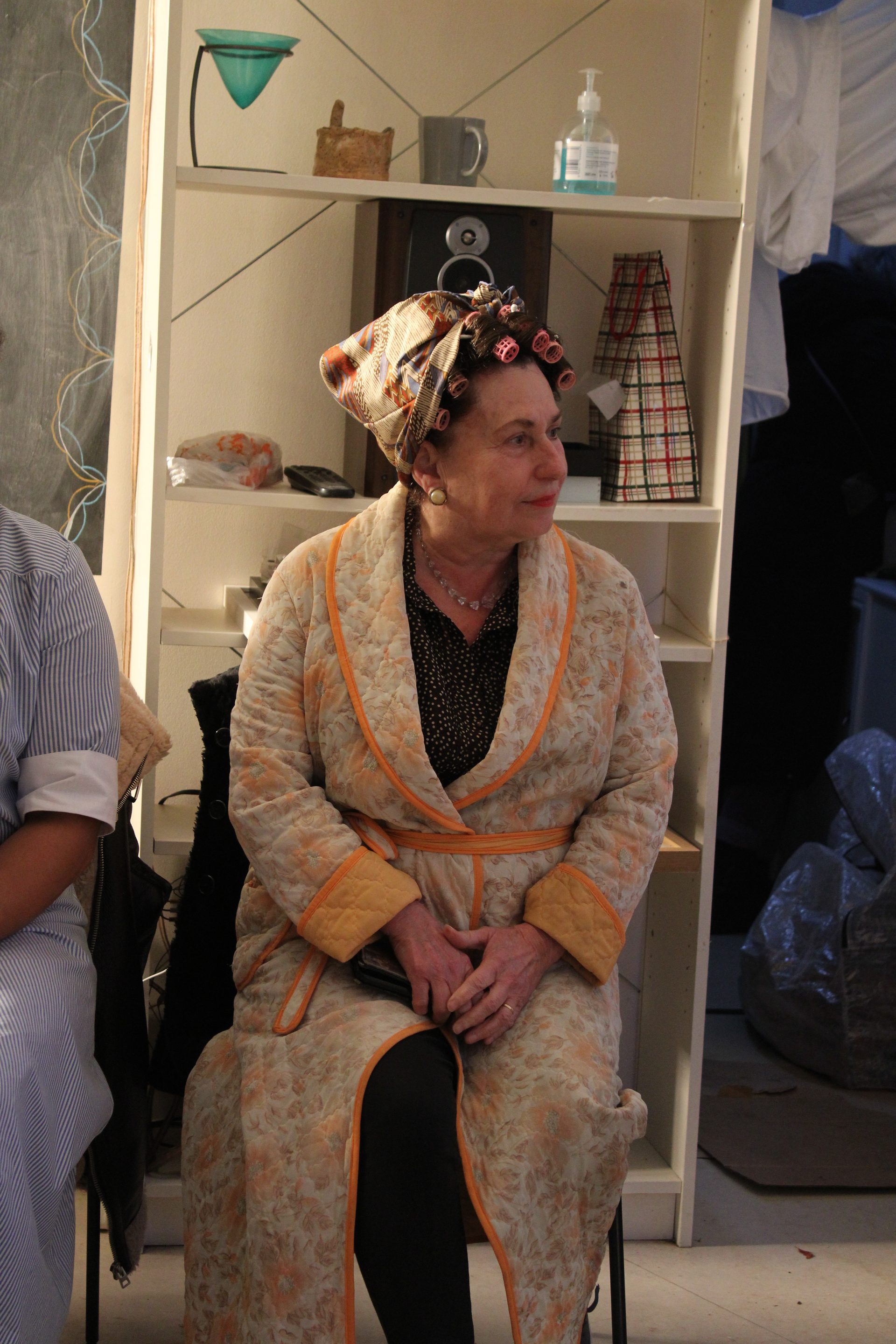 Actress in curlers and dressing gown on kitchen set