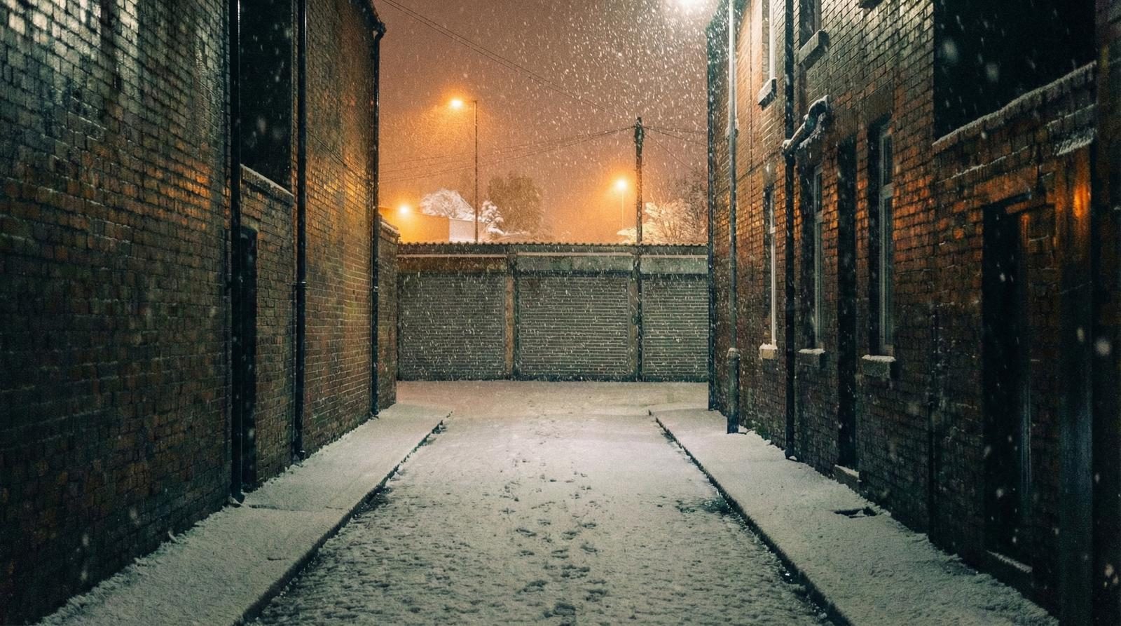A snow-covered Black Country back alley with terraced houses and a warm glow from a doorway — the set of Paths You Walk during the January 2026 shoot