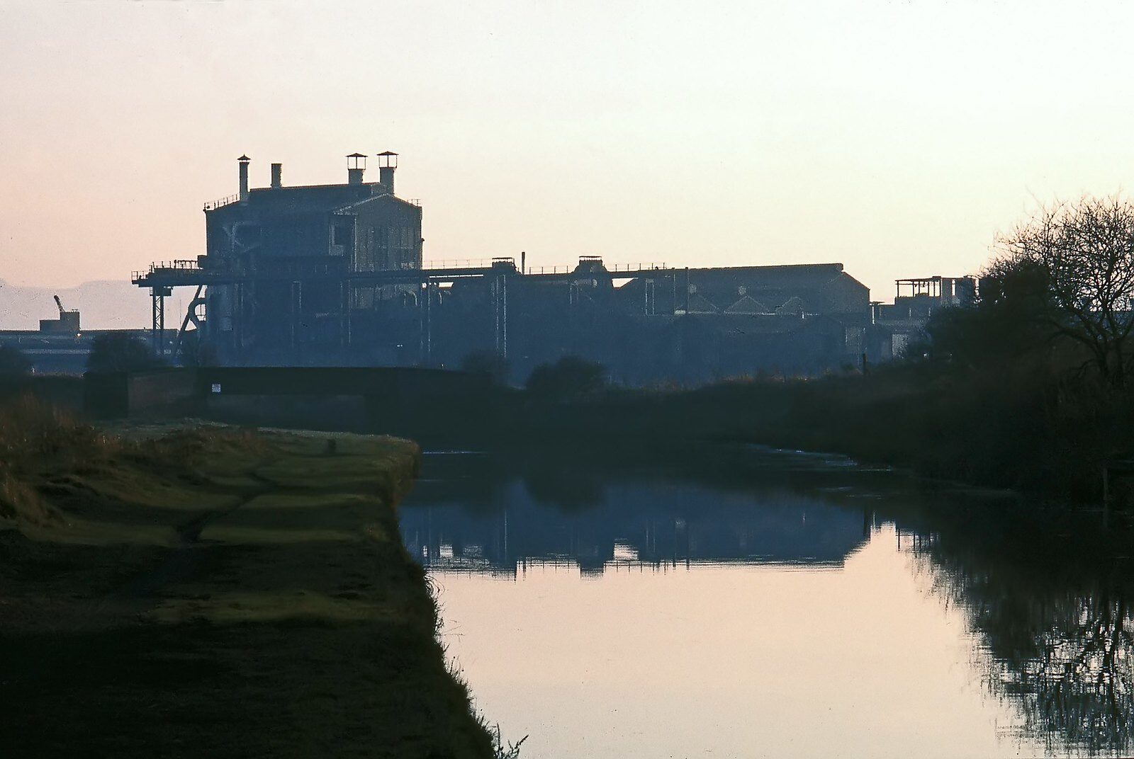 Industrial works reflected in canal at dusk